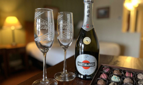 Bottle and 2 wine glasses near a box of truffles